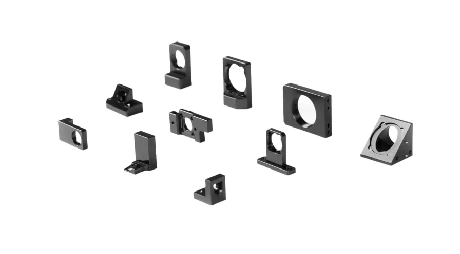 A photo of 10 different custom-machined lens mounts and holders made of aluminum with black anodize finish